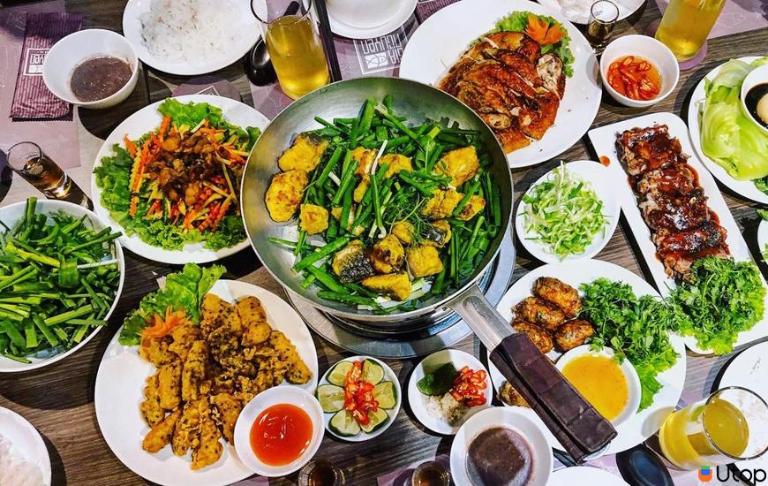 Traditional Hanoi-style Cha Ca being served in a sizzling pan with herbs and vegetables