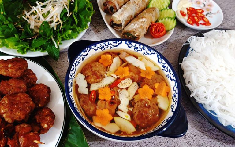 Bun Cha served with fresh herbs and rice noodles on a Ha Noi food tour.