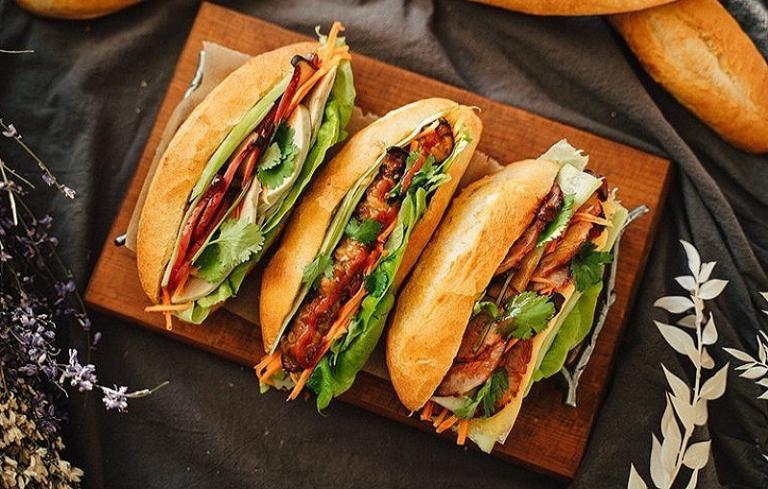 Banh mi made with a baguette, grilled pork or chicken, pickled vegetables, and herbs.