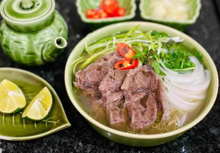 Pho noodle soup with beef, herbs, and broth in a bowl