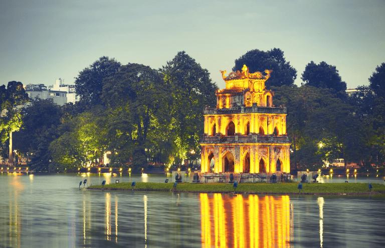 A view of Hoan Kiem Lake illuminated at night, as seen from a motorbike.