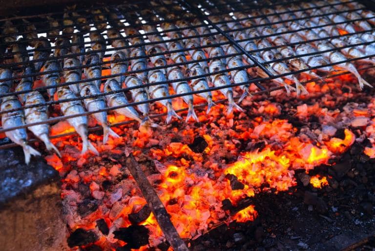 The smoky fragrance of fish grilling over charcoal fills the air with an irresistible aroma.