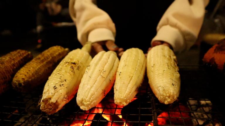 Enjoy roasted corn and sweet potatoes by West Lake at night, a perfect winter street snack.