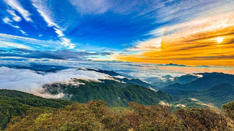 As the sun sets behind Tay Con Linh Peak, the sky transforms into a canvas of fiery colors, enchanting all who witness it.