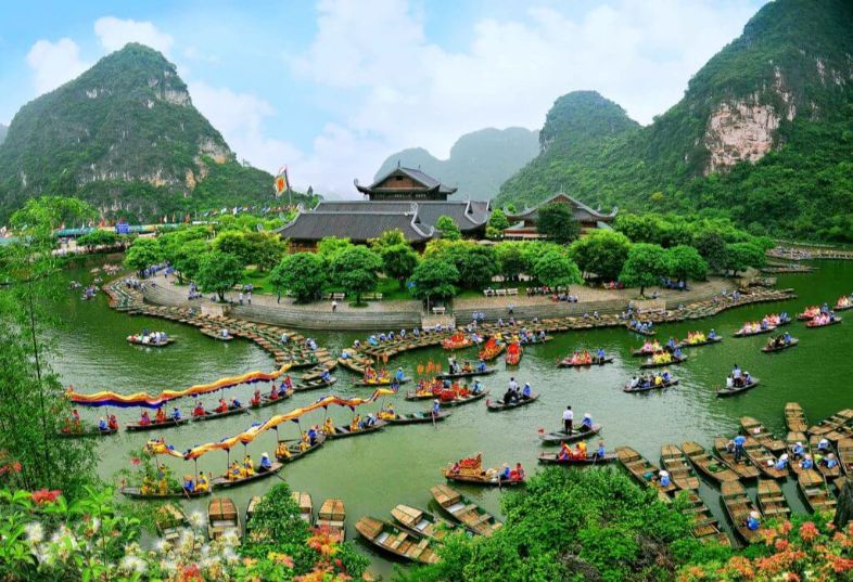Boats navigating the scenic rivers of Tràng An, Ninh Bình, surrounded by towering limestone karsts and lush greenery.
