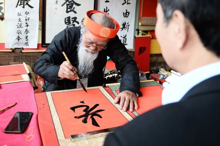 A traditional Vietnamese calligrapher sitting and writing characters at the Temple of Literature in Hanoi.