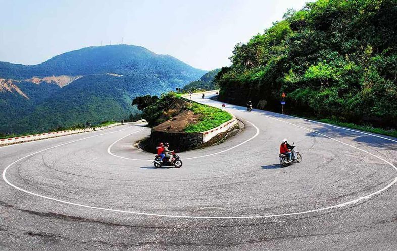 A winding mountain road at Hai Van Pass in Vietnam, surrounded by lush hills and coastal views.