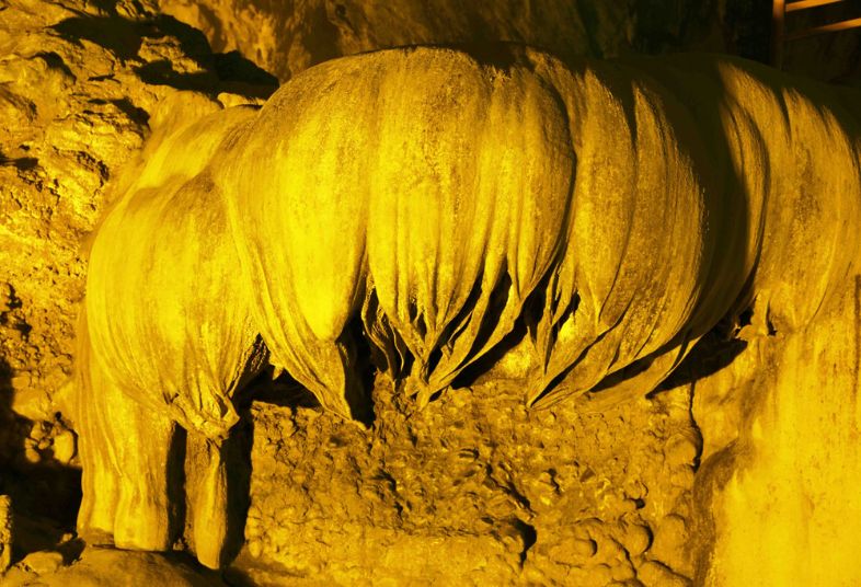 Inside Nguom Ngao Cave in Cao Bằng, Vietnam, showcasing dramatic limestone formations and illuminated pathways.