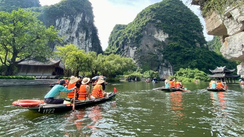 ourists on a small rowing boat navigating the tranquil rivers and limestone caves of Tràng An, Ninh Bình.