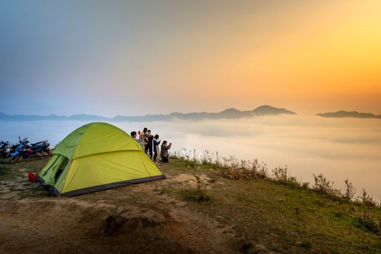 A campsite in Vietnam with tents set among greenery and mountains, capturing a peaceful outdoor atmosphere.